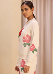 Side view of a woman wearing a cream-colored sweatshirt with vibrant floral embroidery, paired with matching pants, perfect for a stylish and comfortable look.